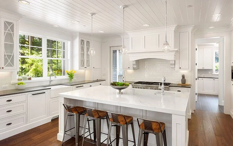 McKelvey Designs Houston kitchen remodel — white shaker cabinetry, marble waterfall island, brass pendant lighting